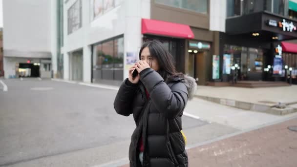 30代の韓国人男性のスローモーションビデオは ソウル 明洞の寒い冬にスマートフォンを操作しています — ストック動画