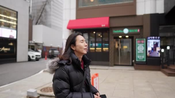寒い冬に韓国の明洞のメインストリートを歩いている30代の韓国人男性のスローモーションビデオ — ストック動画
