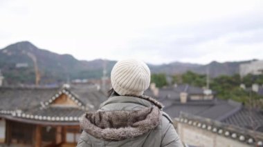 20 'li yaşlarda Filipinli bir kadın Güney Kore, Seul' deki Bukchon Hanok Köyü 'nde geleneksel kasaba manzarasına bakıyor.