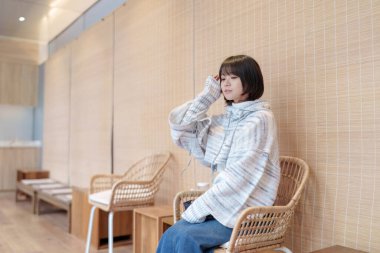  20 'li yaşlarda Çinli bir kadın Hong Kong' da soğuk bir kış günü dinlenme yerinde mola veriyor.