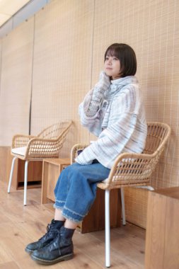  20 'li yaşlarda Çinli bir kadın Hong Kong' da soğuk bir kış günü dinlenme yerinde mola veriyor.