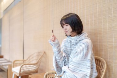  20 'li yaşlarda Çinli bir kadın Hong Kong' da soğuk bir kış günü dinlenme yerinde mola veriyor.