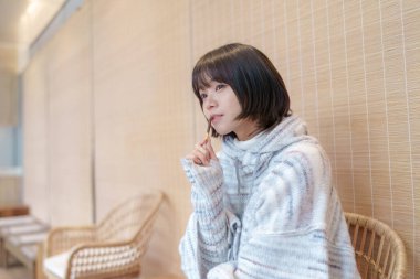  20 'li yaşlarda Çinli bir kadın Hong Kong' da soğuk bir kış günü dinlenme yerinde mola veriyor.