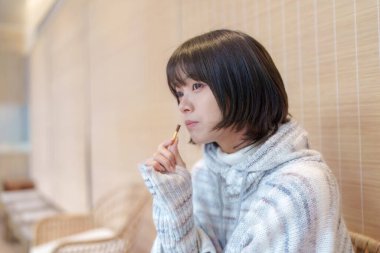  20 'li yaşlarda Çinli bir kadın Hong Kong' da soğuk bir kış günü dinlenme yerinde mola veriyor.