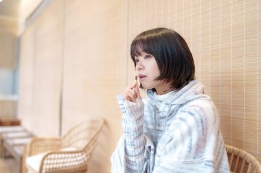  20 'li yaşlarda Çinli bir kadın Hong Kong' da soğuk bir kış günü dinlenme yerinde mola veriyor.