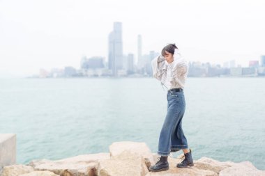 20 'li yaşlarda Çinli bir kadın soğuk kış günü Hong Kong' da sokaklarda, parklarda ve deniz kıyısında yürüyüş yapıyor.