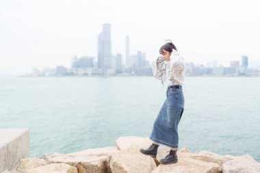 20 'li yaşlarda Çinli bir kadın soğuk kış günü Hong Kong' da sokaklarda, parklarda ve deniz kıyısında yürüyüş yapıyor.