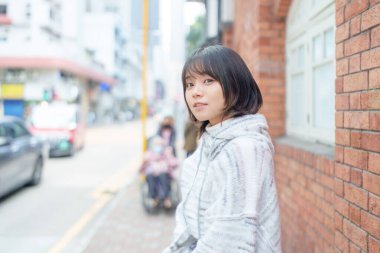 20 'li yaşlarda Çinli bir kadın soğuk kış günü Hong Kong' da sokaklarda, parklarda ve deniz kıyısında yürüyüş yapıyor.