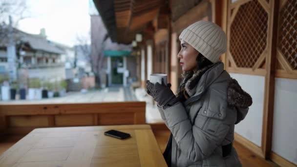 20代のフィリピン人女性のスローモーションビデオは 韓国ソウルの北村ハノック村で伝統的な町でお茶を飲んだ後に休憩を取ります — ストック動画