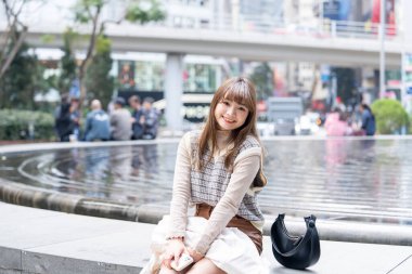 20 'li yaşlarda Çinli bir kadın Hong Kong' da bir parkta mola veriyor.