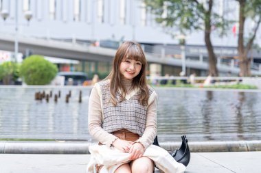 20 'li yaşlarda Çinli bir kadın Hong Kong' da bir parkta mola veriyor.