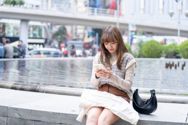 20 'li yaşlarda Çinli bir kadın Hong Kong' da bir parkta mola veriyor.