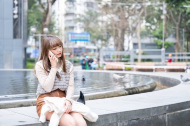 20 'li yaşlarda Çinli bir kadın Hong Kong' da bir parkta mola veriyor.