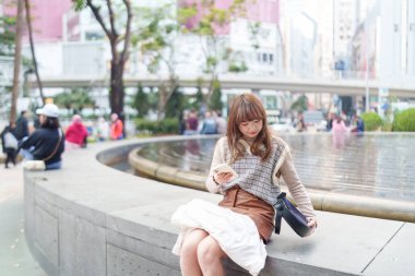 20 'li yaşlarda Çinli bir kadın Hong Kong' da bir parkta mola veriyor.