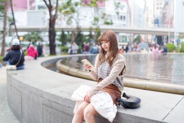 20 'li yaşlarda Çinli bir kadın Hong Kong' da bir parkta mola veriyor.