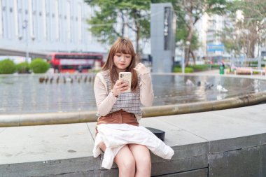 20 'li yaşlarda Çinli bir kadın Hong Kong' da bir parkta mola veriyor.