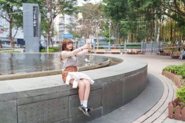 20 'li yaşlarda Çinli bir kadın Hong Kong' da bir parkta mola veriyor.