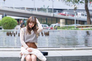 20 'li yaşlarda Çinli bir kadın Hong Kong' da bir parkta mola veriyor.