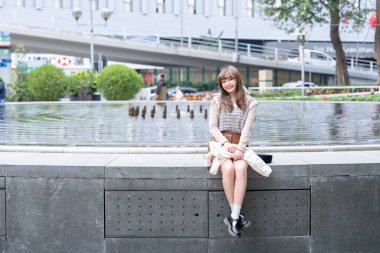 20 'li yaşlarda Çinli bir kadın Hong Kong' da bir parkta mola veriyor.