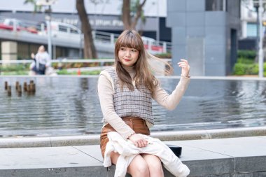 20 'li yaşlarda Çinli bir kadın Hong Kong' da bir parkta mola veriyor.