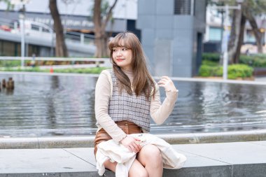 20 'li yaşlarda Çinli bir kadın Hong Kong' da bir parkta mola veriyor.