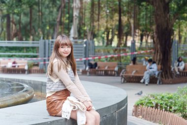 20 'li yaşlarda Çinli bir kadın Hong Kong' da bir parkta mola veriyor.