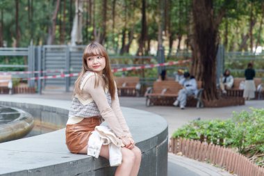 20 'li yaşlarda Çinli bir kadın Hong Kong' da bir parkta mola veriyor.