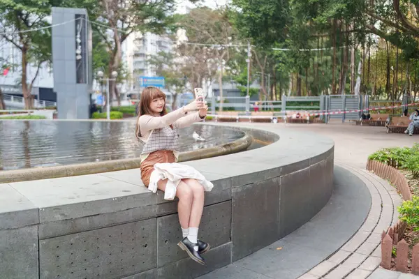 20 'li yaşlarda Çinli bir kadın Hong Kong' da bir parkta mola veriyor.