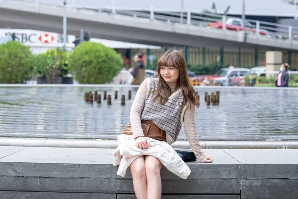 20 'li yaşlarda Çinli bir kadın Hong Kong' da bir parkta mola veriyor.