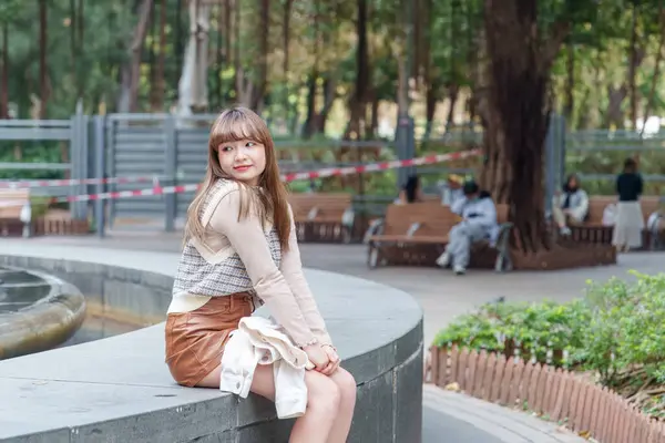 20 'li yaşlarda Çinli bir kadın Hong Kong' da bir parkta mola veriyor.