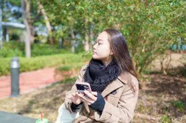 20 'li yaşlarda Çinli bir kadın Hong Kong' da bir parkta mola veriyor.