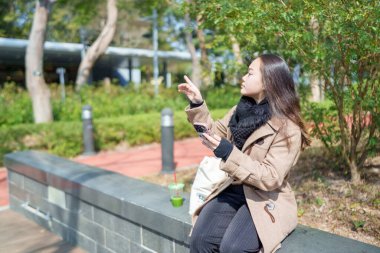 20 'li yaşlarda Çinli bir kadın Hong Kong' da bir parkta mola veriyor.