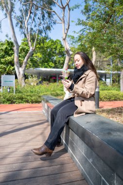20 'li yaşlarda Çinli bir kadın Hong Kong' da bir parkta mola veriyor.