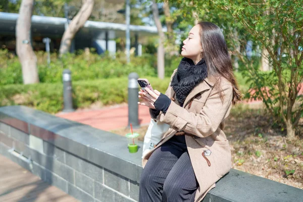 20 'li yaşlarda Çinli bir kadın Hong Kong' da bir parkta mola veriyor.
