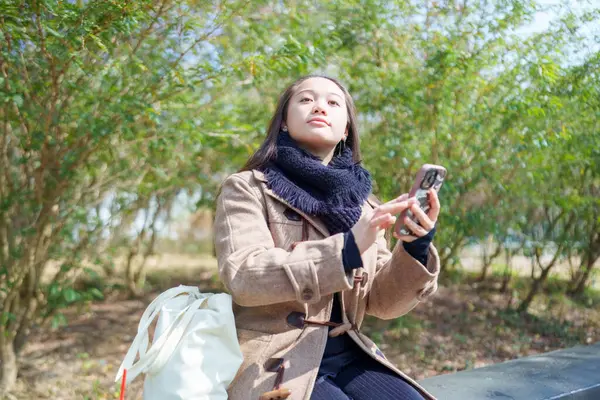 20 'li yaşlarda Çinli bir kadın Hong Kong' da bir parkta mola veriyor.