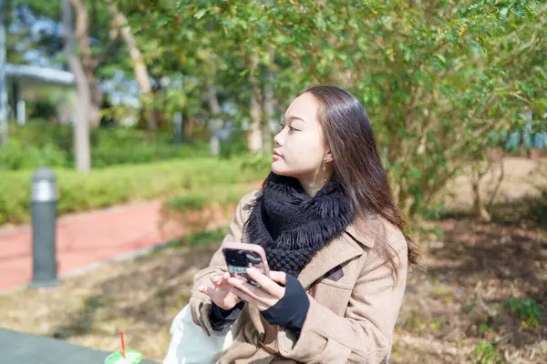 20 'li yaşlarda Çinli bir kadın Hong Kong' da bir parkta mola veriyor.