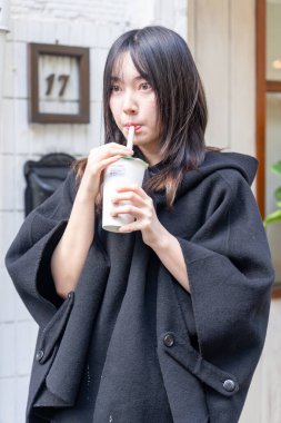 Tayvan 'ın Taipei şehrindeki Zhongshan İstasyonunda 20' li yaşlarda genç bir Tayvanlı kadın tapyoka içiyor.