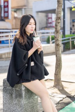 Tayvan 'ın Taipei şehrindeki Zhongshan İstasyonunda 20' li yaşlarda genç bir Tayvanlı kadın tapyoka içiyor.