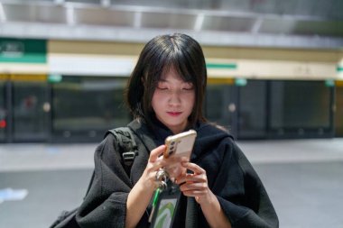 20 'li yaşlarda Tayvanlı genç bir üniversite öğrencisi akıllı telefonunu Taipei, Tayvan' da bir metro istasyonunda ya da trende kullanıyor.