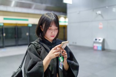 20 'li yaşlarda Tayvanlı genç bir üniversite öğrencisi akıllı telefonunu Taipei, Tayvan' da bir metro istasyonunda ya da trende kullanıyor.