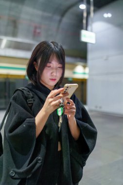 20 'li yaşlarda Tayvanlı genç bir üniversite öğrencisi akıllı telefonunu Taipei, Tayvan' da bir metro istasyonunda ya da trende kullanıyor.