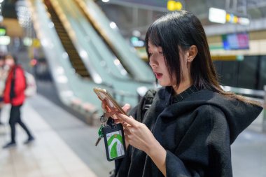 20 'li yaşlarda Tayvanlı genç bir üniversite öğrencisi akıllı telefonunu Taipei, Tayvan' da bir metro istasyonunda ya da trende kullanıyor.