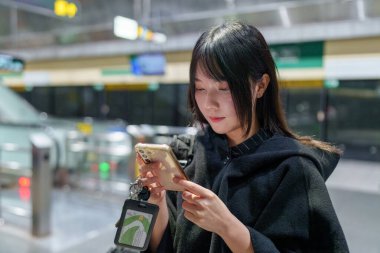 20 'li yaşlarda Tayvanlı genç bir üniversite öğrencisi akıllı telefonunu Taipei, Tayvan' da bir metro istasyonunda ya da trende kullanıyor.
