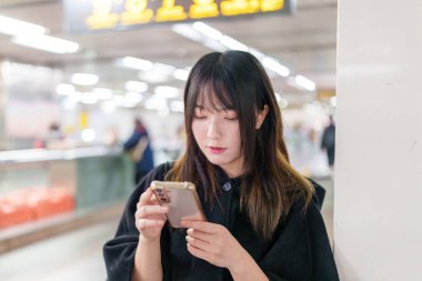 20 'li yaşlarda Tayvanlı genç bir üniversite öğrencisi akıllı telefonunu Taipei, Tayvan' da bir metro istasyonunda ya da trende kullanıyor.