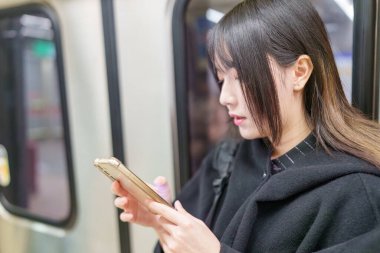 20 'li yaşlarda Tayvanlı genç bir üniversite öğrencisi akıllı telefonunu Taipei, Tayvan' da bir metro istasyonunda ya da trende kullanıyor.