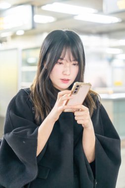 20 'li yaşlarda Tayvanlı genç bir üniversite öğrencisi akıllı telefonunu Taipei, Tayvan' da bir metro istasyonunda ya da trende kullanıyor.