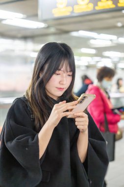 20 'li yaşlarda Tayvanlı genç bir üniversite öğrencisi akıllı telefonunu Taipei, Tayvan' da bir metro istasyonunda ya da trende kullanıyor.