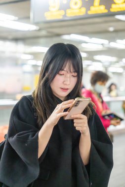 20 'li yaşlarda Tayvanlı genç bir üniversite öğrencisi akıllı telefonunu Taipei, Tayvan' da bir metro istasyonunda ya da trende kullanıyor.