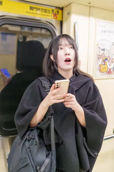 20 'li yaşlarda Tayvanlı genç bir üniversite öğrencisi akıllı telefonunu Taipei, Tayvan' da bir metro istasyonunda ya da trende kullanıyor.