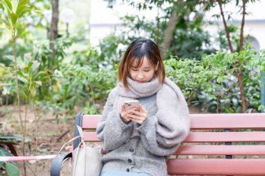 20 'li yaşlarda Çinli bir kadın kışın soğuk olan Hong Kong' da, Tsim Sha Tsui 'de bir parkta vakit geçiriyor.